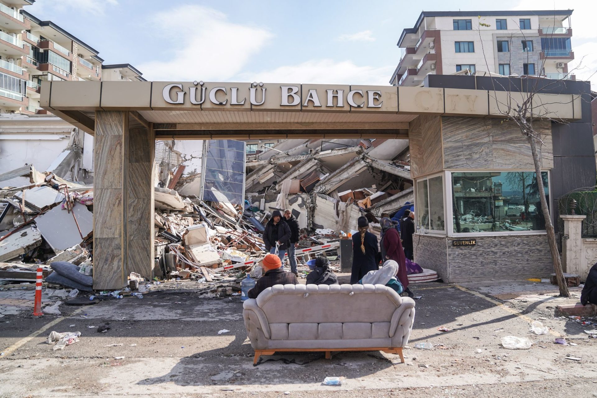 People sit on a sofa in front of a destroyed building. In the earthquake areas in Syria and Turkey, more and more bodies are being recovered from the remains of collapsed buildings in the search for buried people. Photo: Ibrahim Oner/SOPA Images via ZUMA Press Wire/dpa