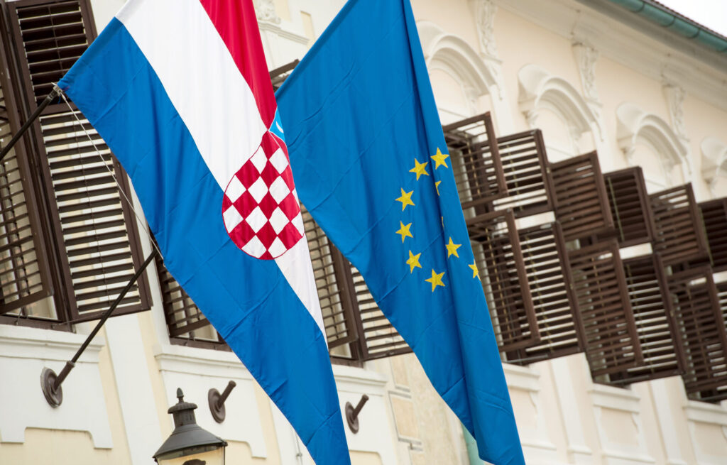 The Croatian and EU flags next to each other on a building.