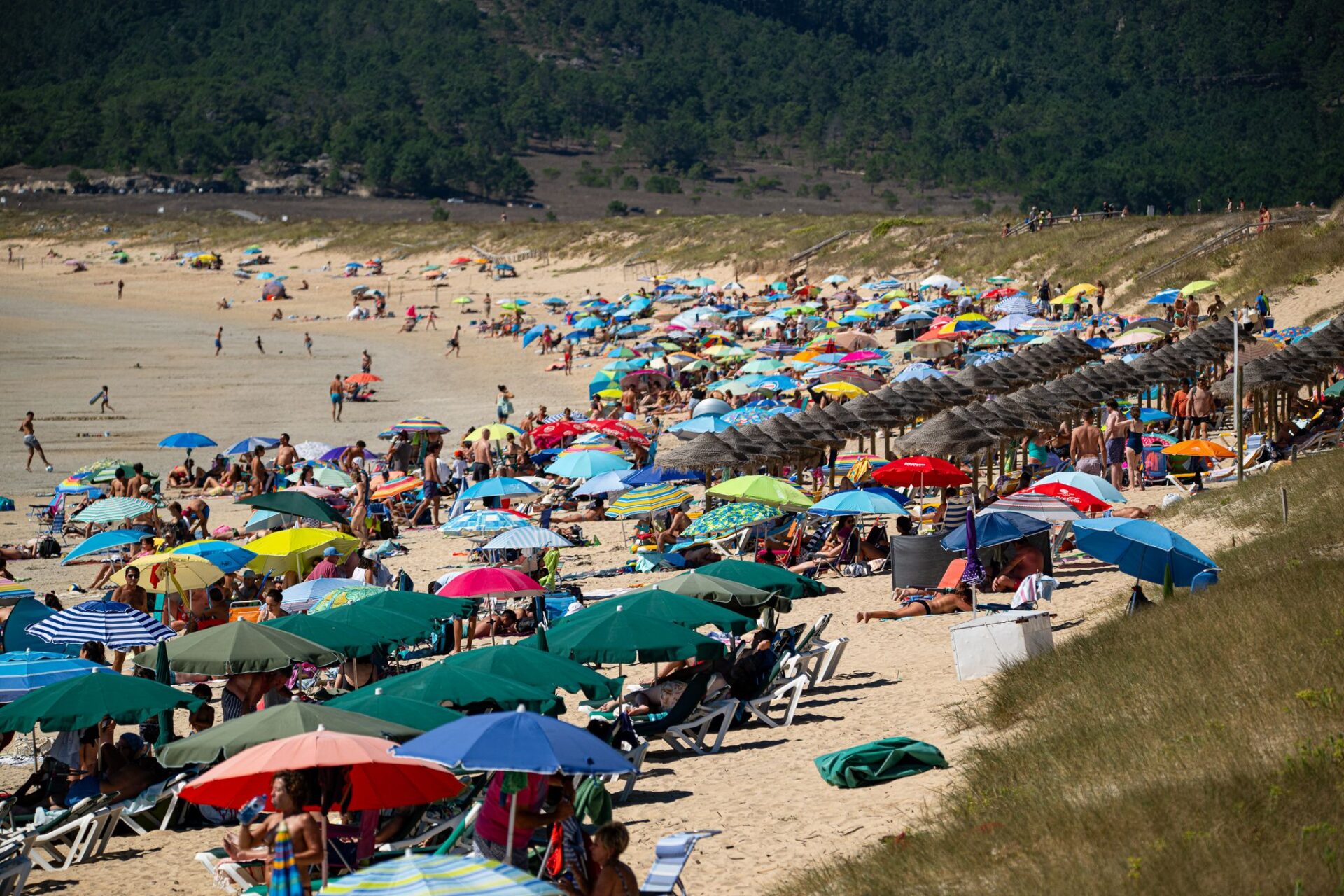Several people take shelter from the sun under umbrellas on a beach in Pontevedra. Spain is being hit by the fourth heatwave of the summer and it is expected to continue at least until Thursday with an increased risk of forest fires, the weather service AEMET said on Monday.