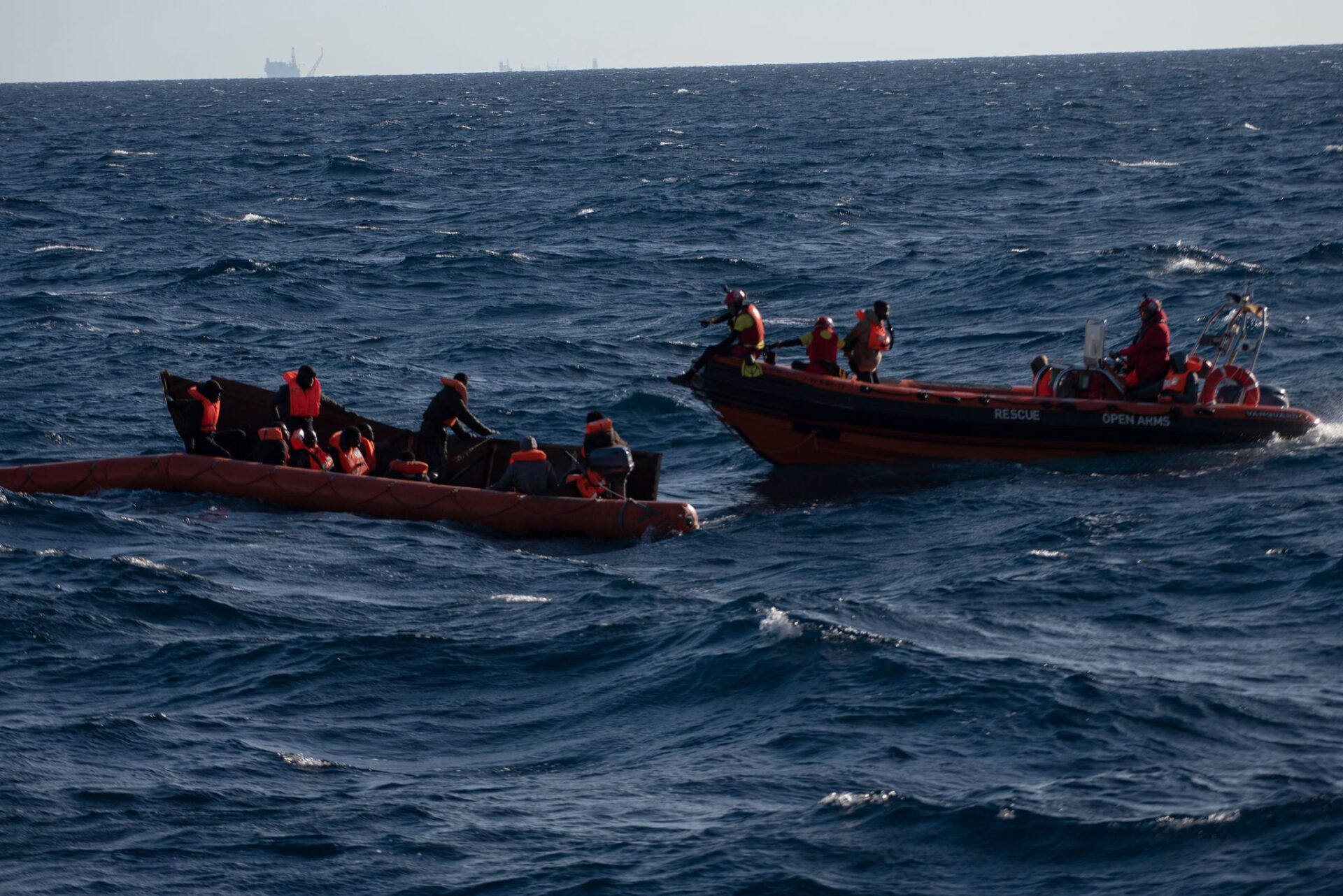 Mehrere Migranten sitzen in einem Boot im Mittelmeer während Rettungskräfte versuchen ihnen zu helfen. 60 Migranten wurden am Nachmittag von der Besatzung des Schiffes der Nichtregierungsorganisationen (NGO) Open Arms gerettet.