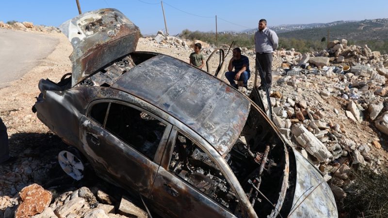 Tres palestinos observan un coche incendiado por colonos israelíes en el pueblo de Qarawa, cerca de Salfit, en Cisjordania ocupada, el pasado 12 de diciembre de 2023. EFE/EPA/ALAA BADARNEH