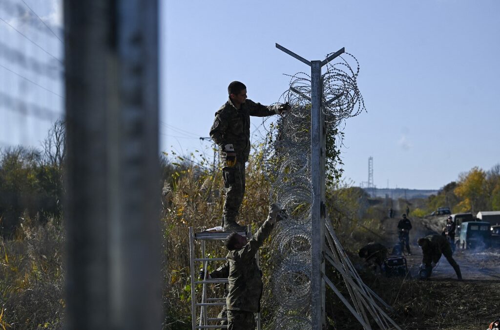 Bulgarian army personnel repair the barbed wire wall border fence on the Bulgaria-Turkey border near the village of Matochina on November 4, 2021. - Bulgaria on November 1, 2021, deployed 350 soldiers to the border with Turkey to help police cope with the growing influx of migrants, the defence minister announced. (Photo by Nikolay DOYCHINOV / AFP)