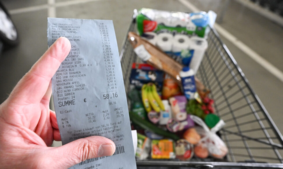 Un consumidor sostiene un recibo en la mano tras comprar en un supermercado. Foto: Bernd Weißbrod/dpa