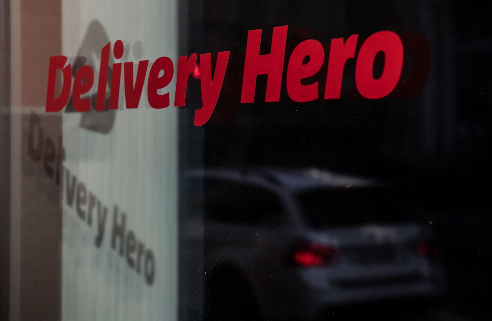 Das Logo und der Schriftzug des Essenslieferdienstes Delivery Hero spiegelt sich in einer Fensterscheibe. (zu dpa: «EU-Kommission eröffnet Untersuchung gegen Delivery Hero»)