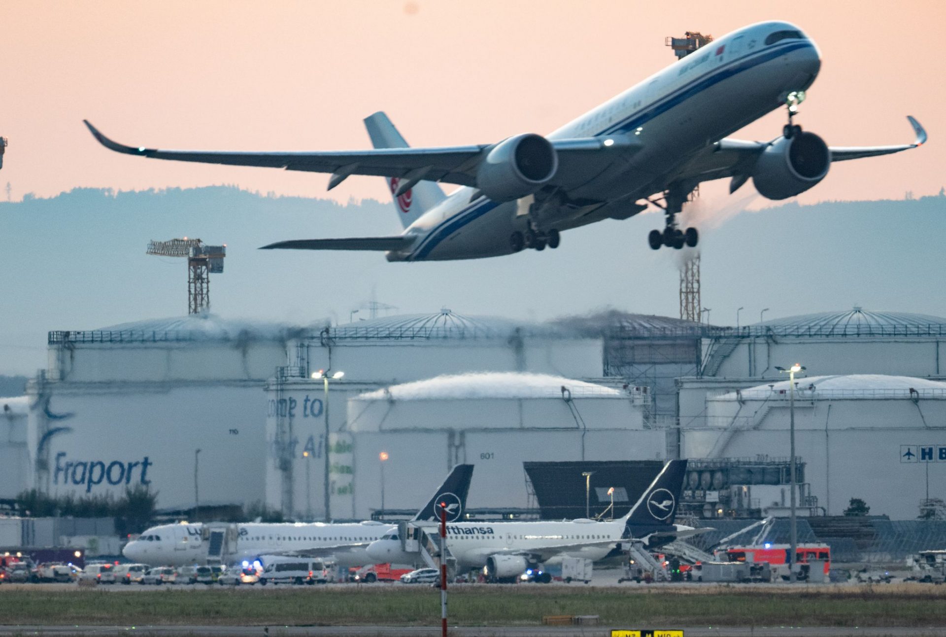 Nachdem das Flugzeug unplanmäßig zum Flughafen zurückkehren musste, stehen Feuerwehrfahrzeuge an dem gelandeten Airbus der Lufthansa.