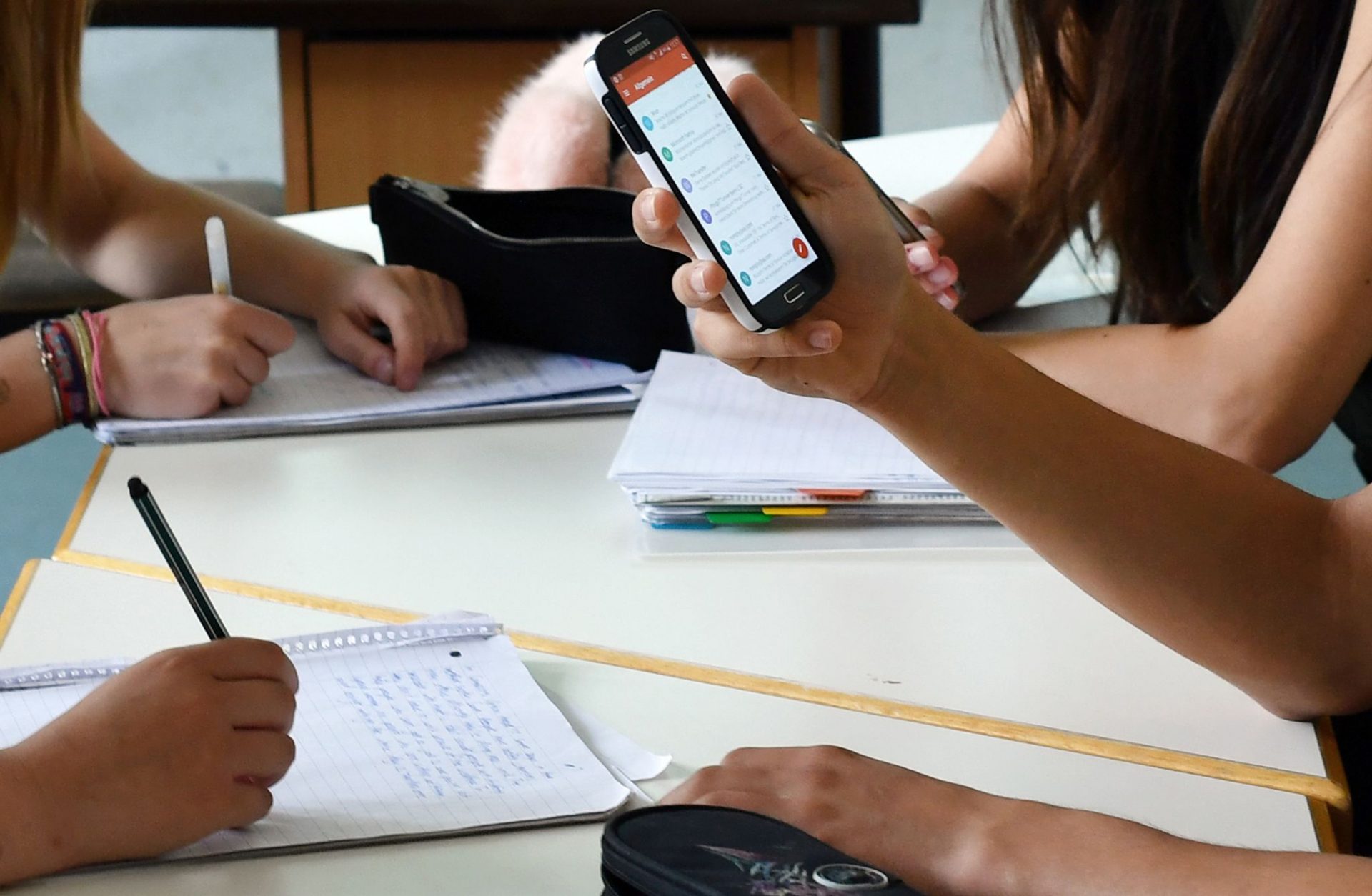 A student holds a mobile phone during a lesson at a classroom.  Schools in the Netherlands began a complete nationwide ban on mobile phones on 02 September.