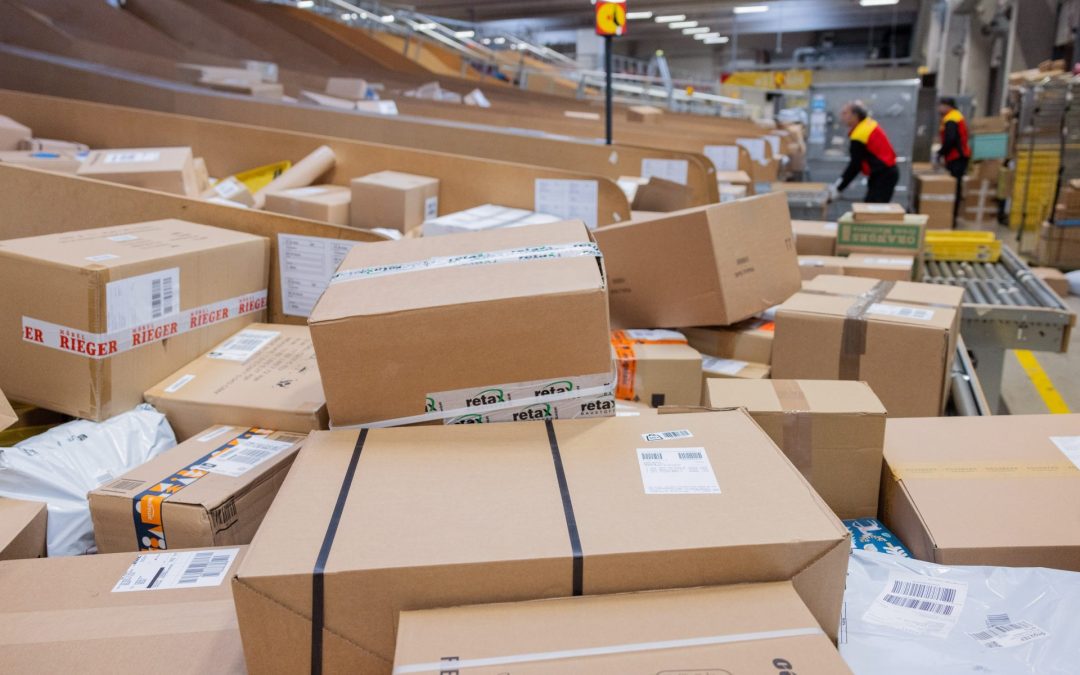 Parcel delivery drivers sort and load parcels into delivery vehicles at a Deutsche Post DHL delivery depot. Photo: picture alliance/dpa/Rolf Vennenbernd